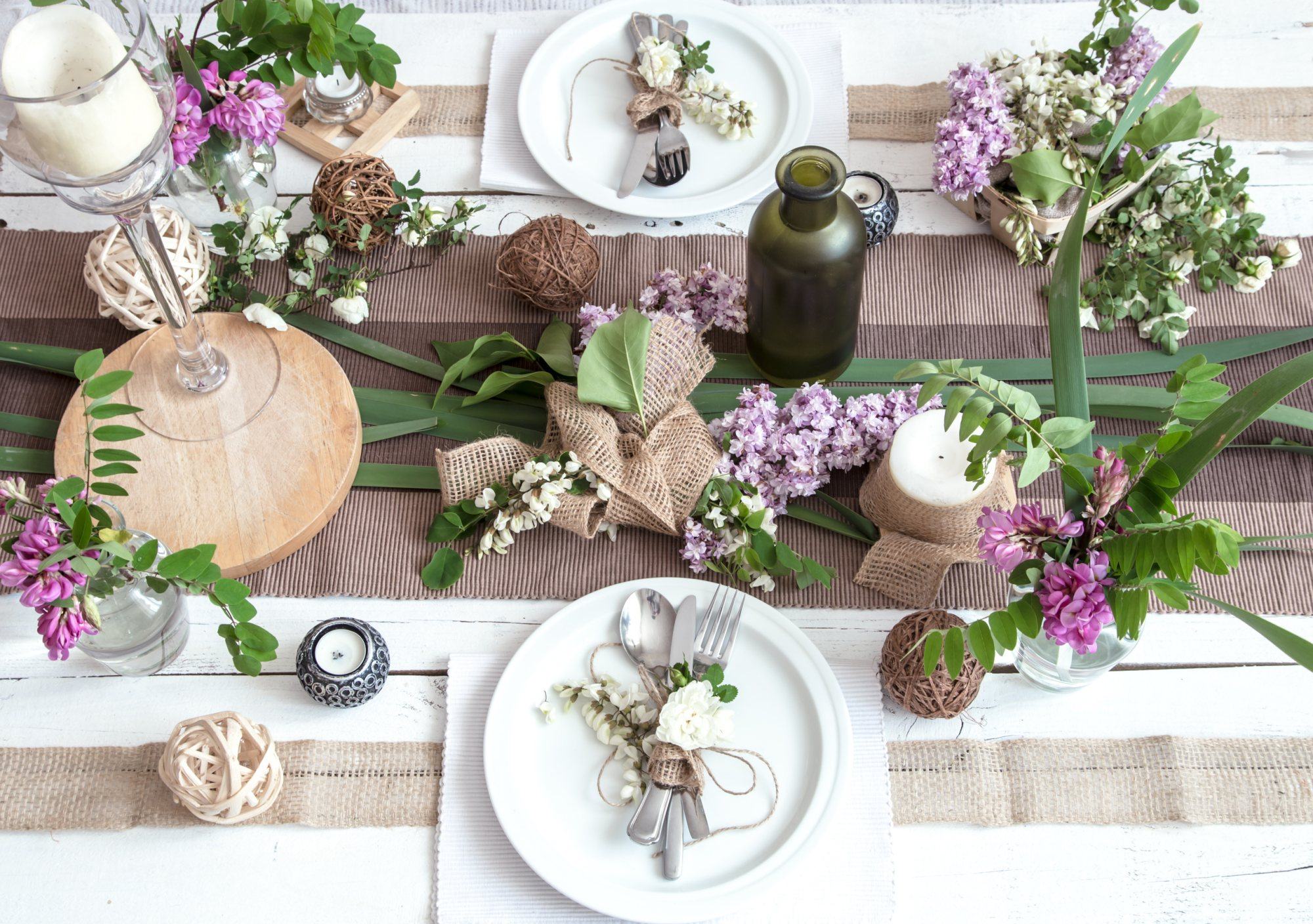 A rustic table setting with flowers, candles, and utensils