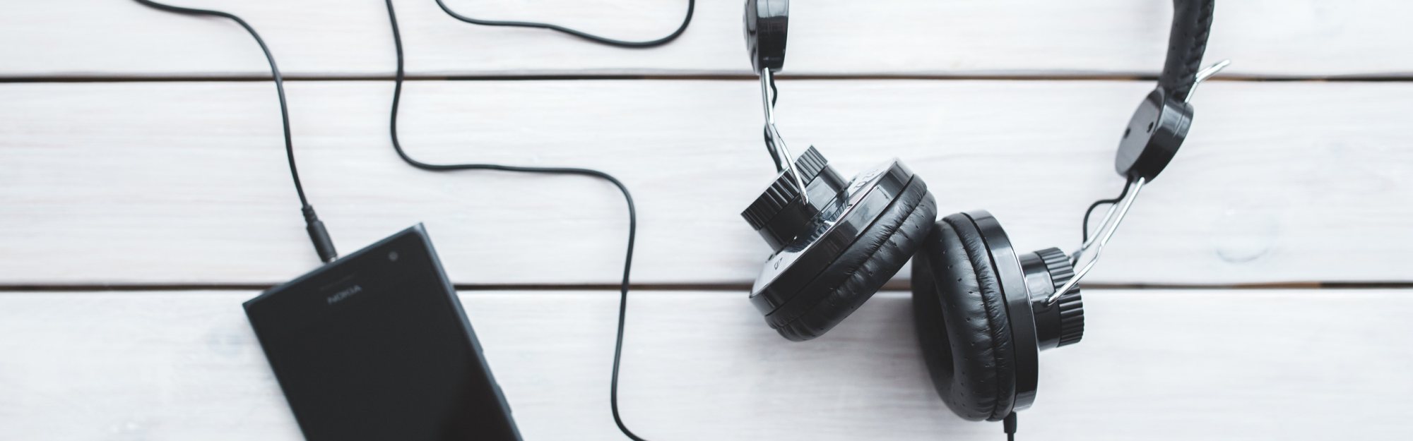 Wireless microphone and headphones on a wooden surface.