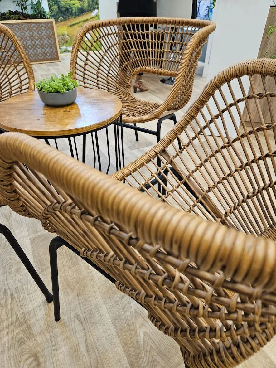 Two rattan chairs and a wooden table in a bright interior.