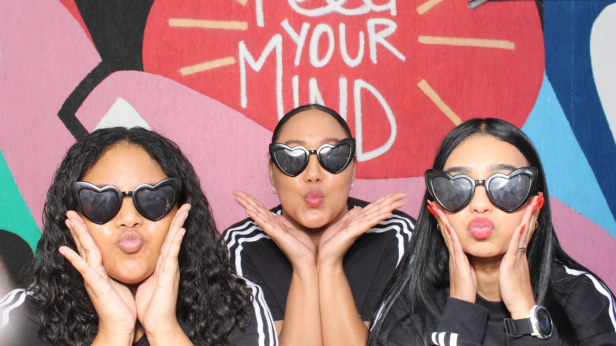 Three women with heart-shaped sunglasses posing playfully