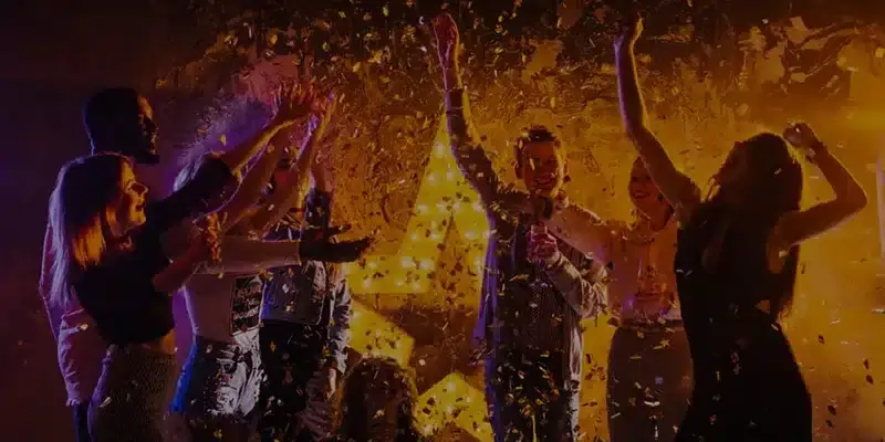 Group of people celebrating with confetti and a vintage photo booth.