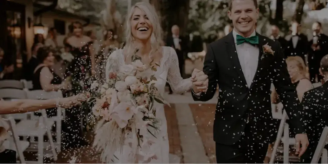 Couple walking down the aisle with confetti at wedding