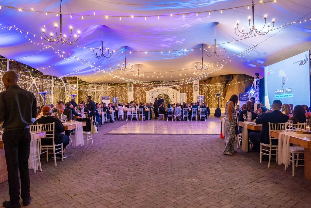 Outdoor event setup with tables, lights, and guests at Rhebokskloof Estate