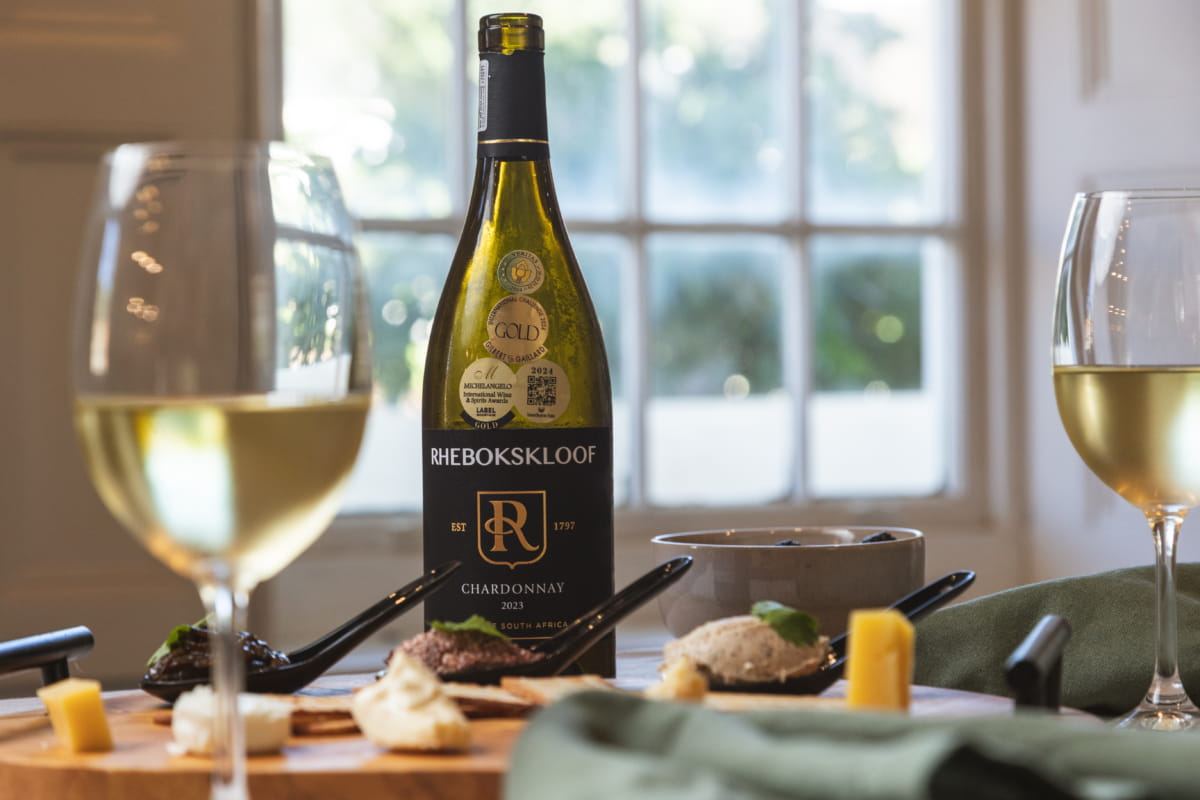 Bottle of Rhebokskloof Chardonnay with tasting snacks on a wooden platter