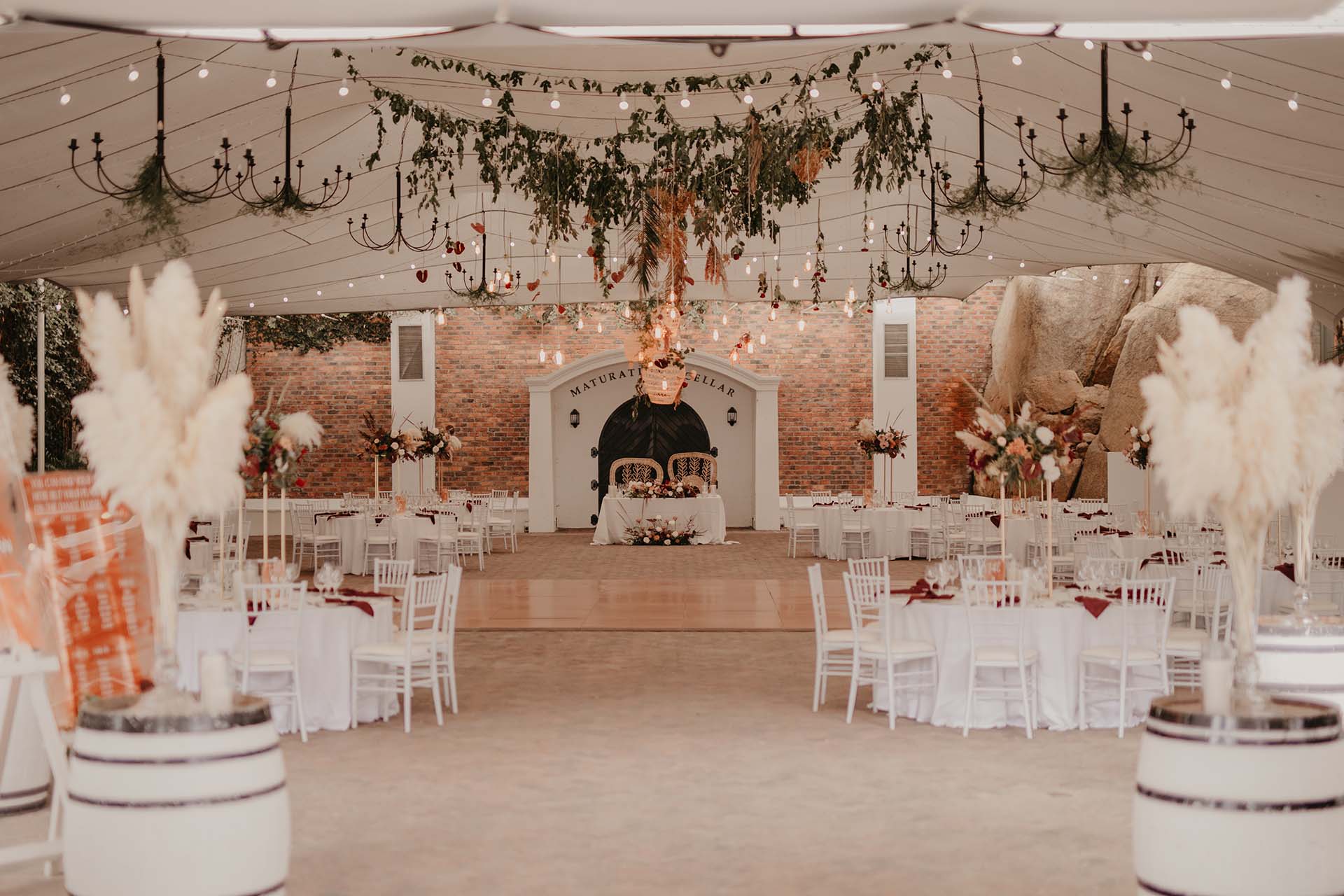 Indoor venue setup with tables, chandeliers, and decor