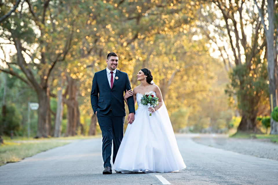 Couple walking together on a road, surrounded by trees