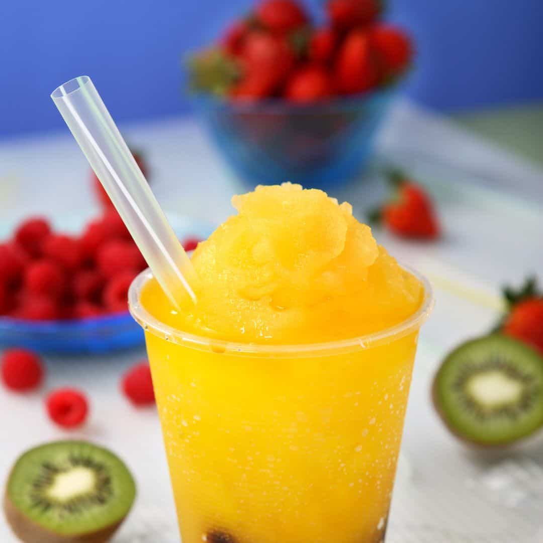 Close-up of a slushy drink with fruits in the background
