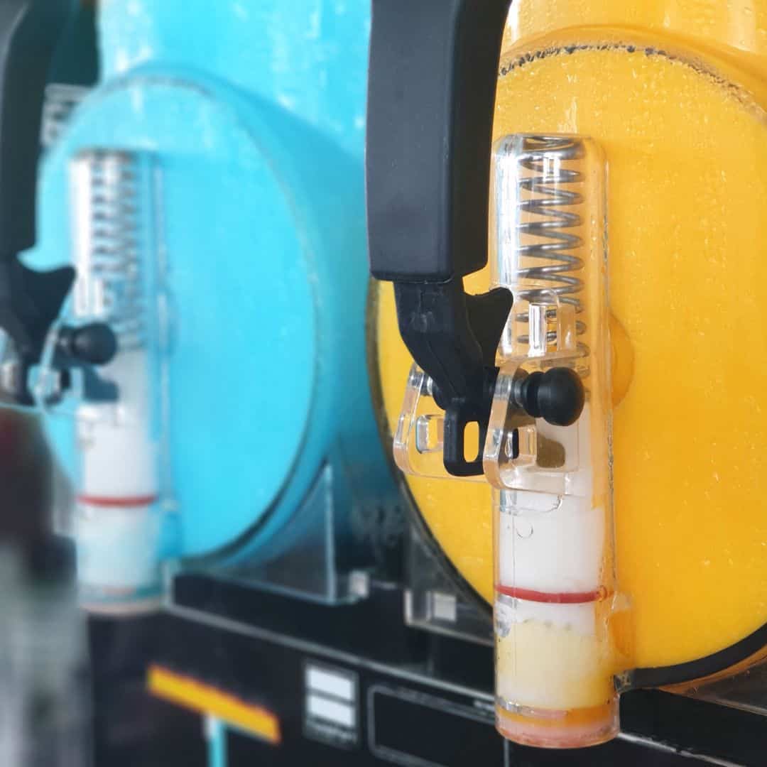 Two slushy machines in blue and yellow with dispensers.