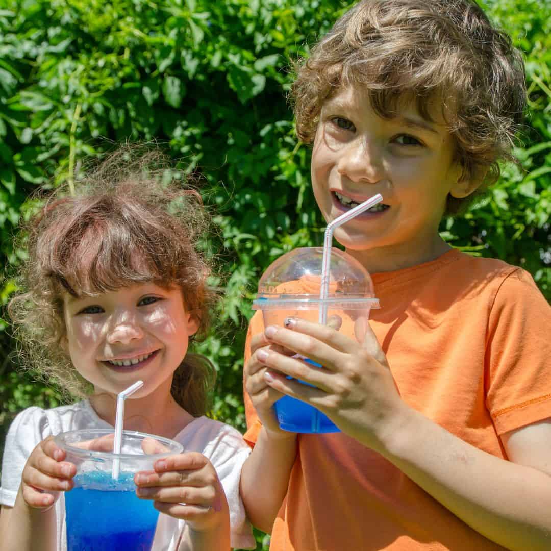 Two children holding slushy drinks with straws