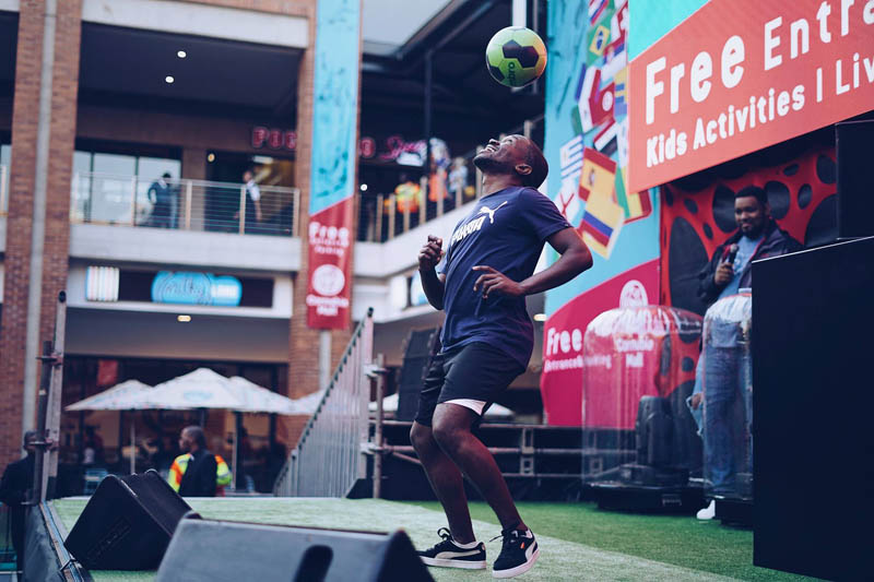 Performer balancing a soccer ball on stage in a festive setting