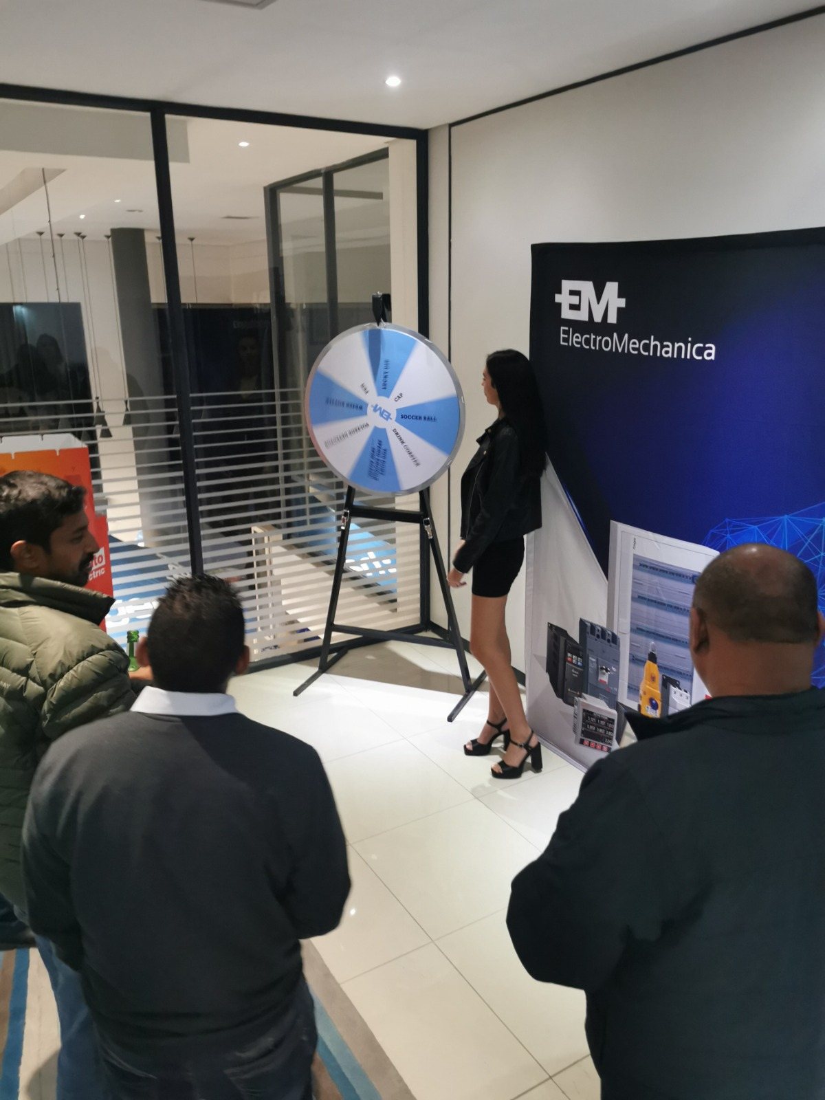 A spin wheel setup at an event with attendees gathered around.