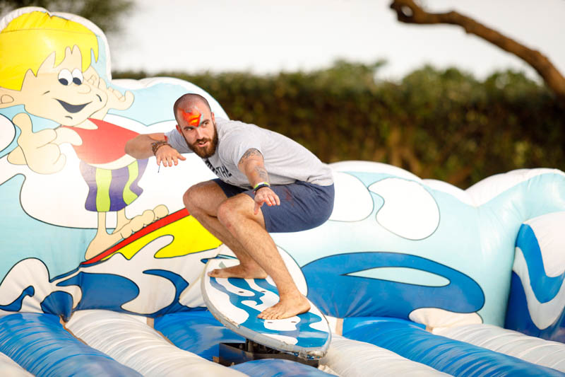 Individual surfing on mechanical surf simulator at an event.