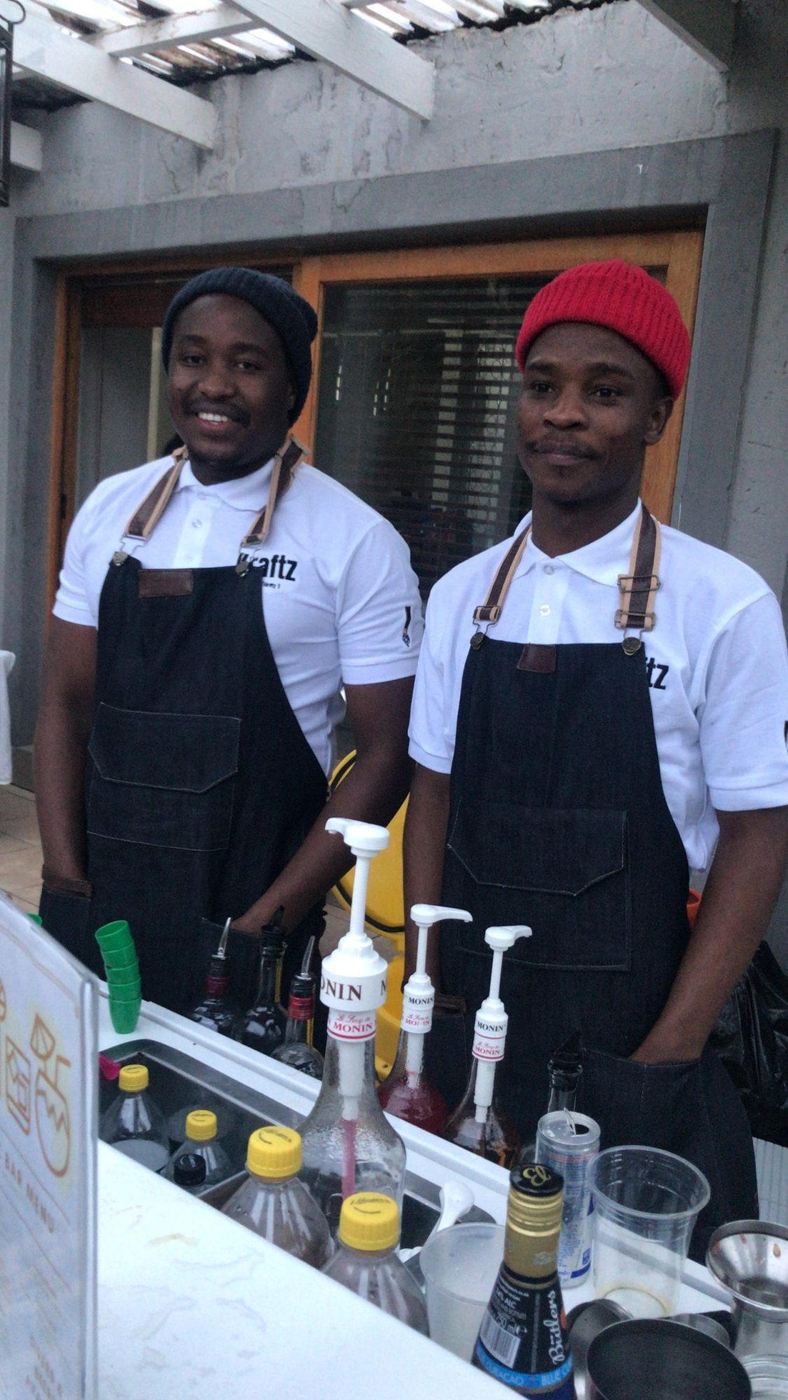 Two bartenders in branded uniforms at a mobile bar.