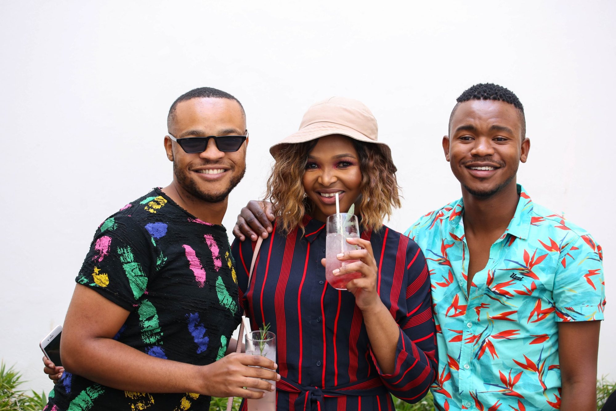 Three guests smiling while holding cocktails outdoors