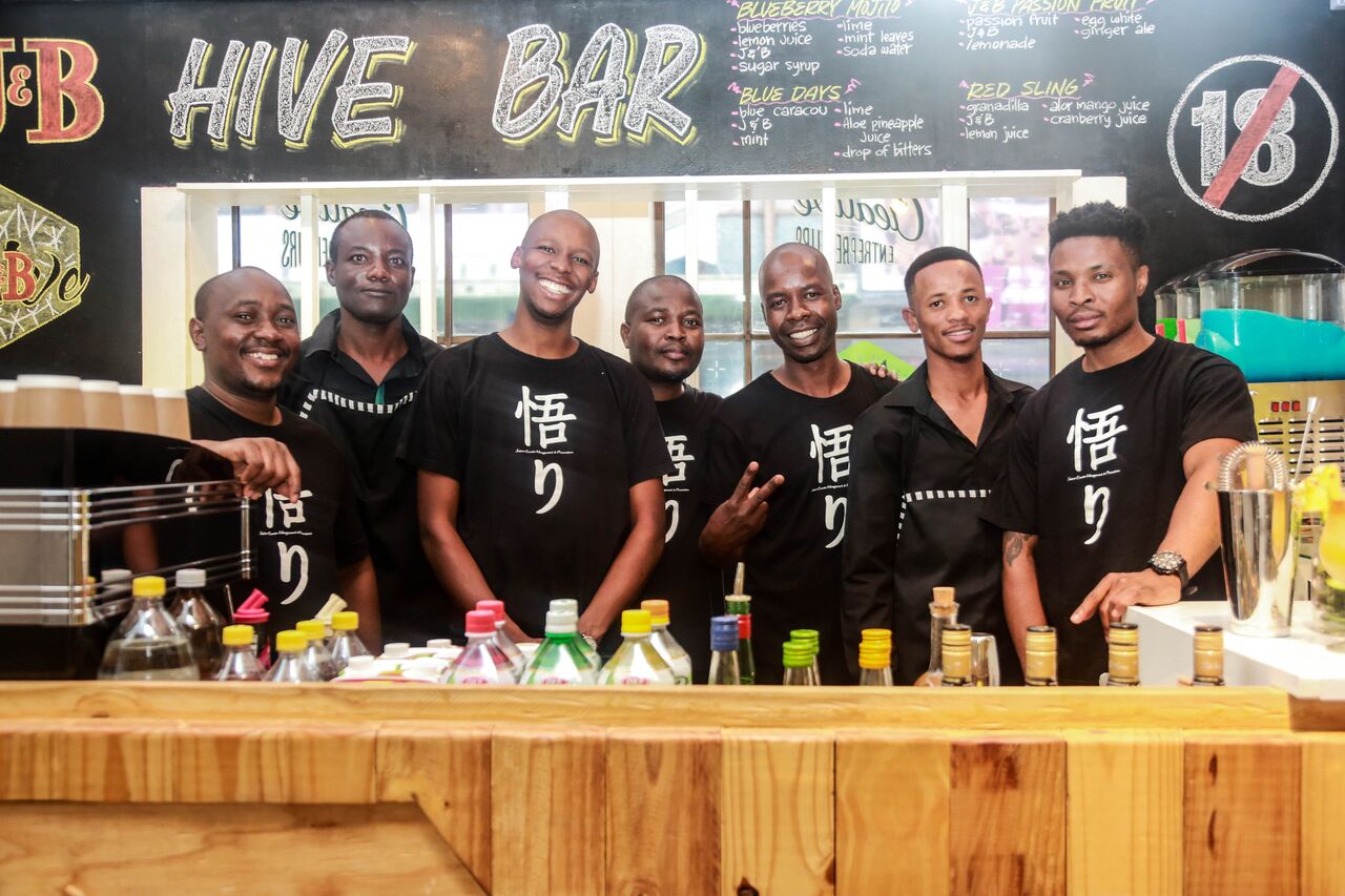 Seven bartenders in black shirts at Hive Bar.