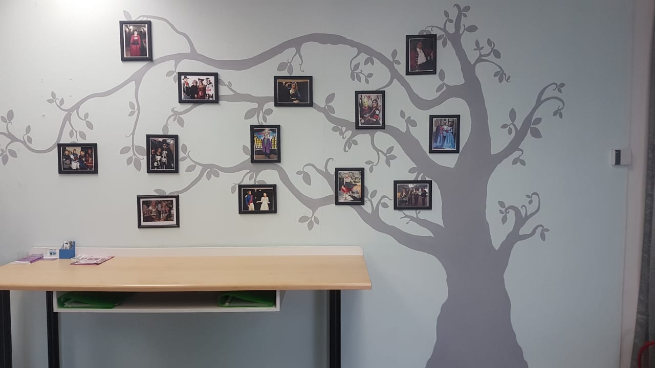 Photos of costumes displayed on a tree-themed wall