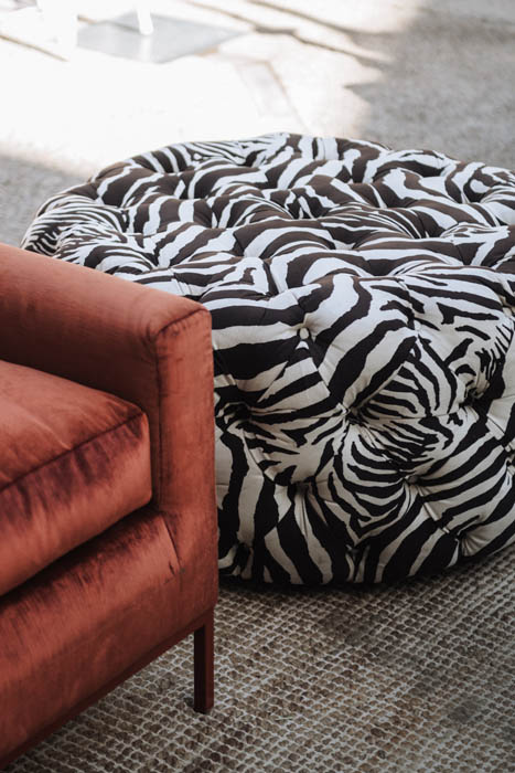 Zebra patterned pouf next to an orange sofa