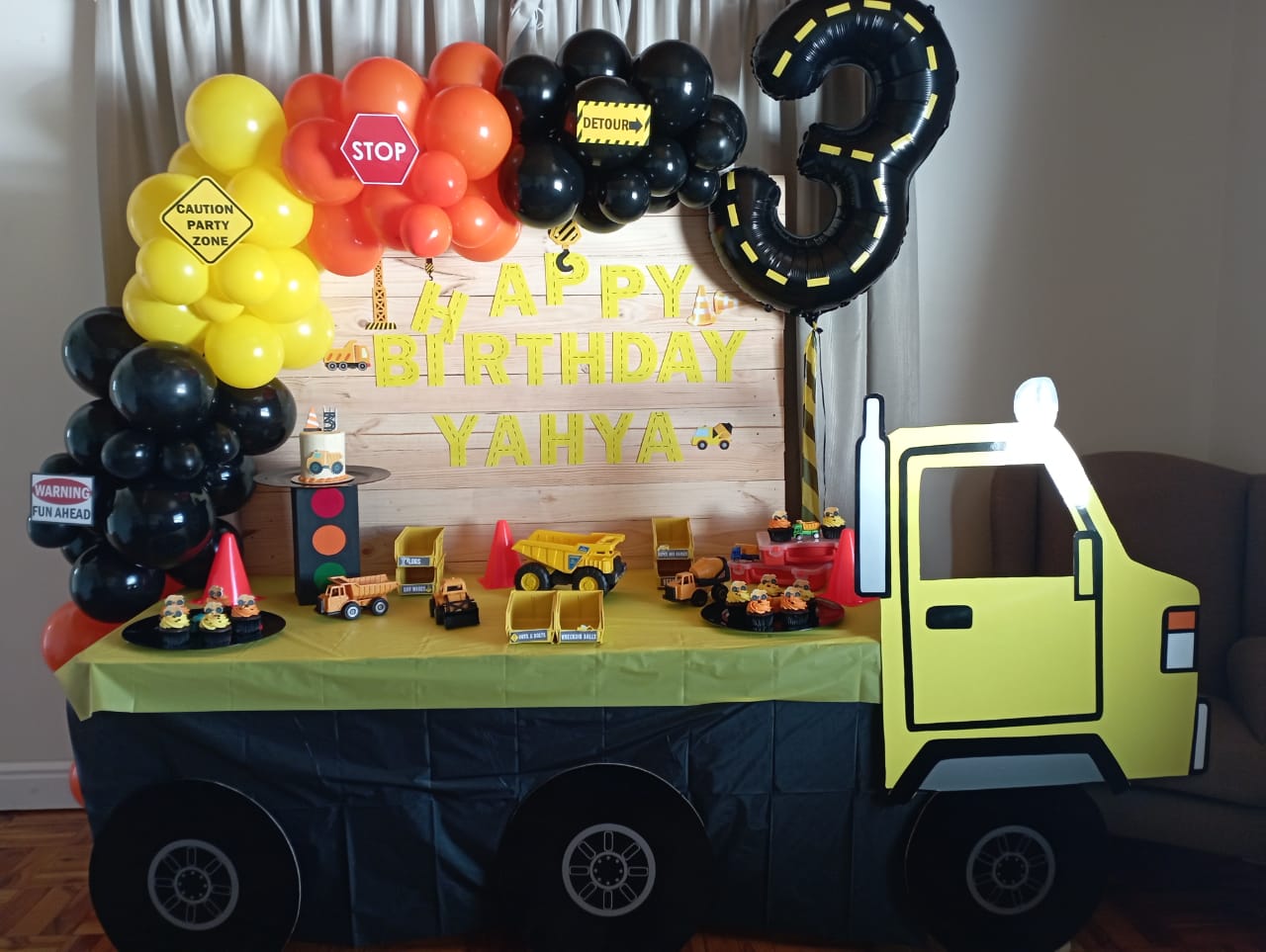 Construction-themed birthday setup with trucks and balloons