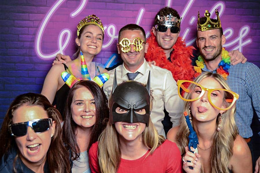 Group of people posing with fun props in a photo booth