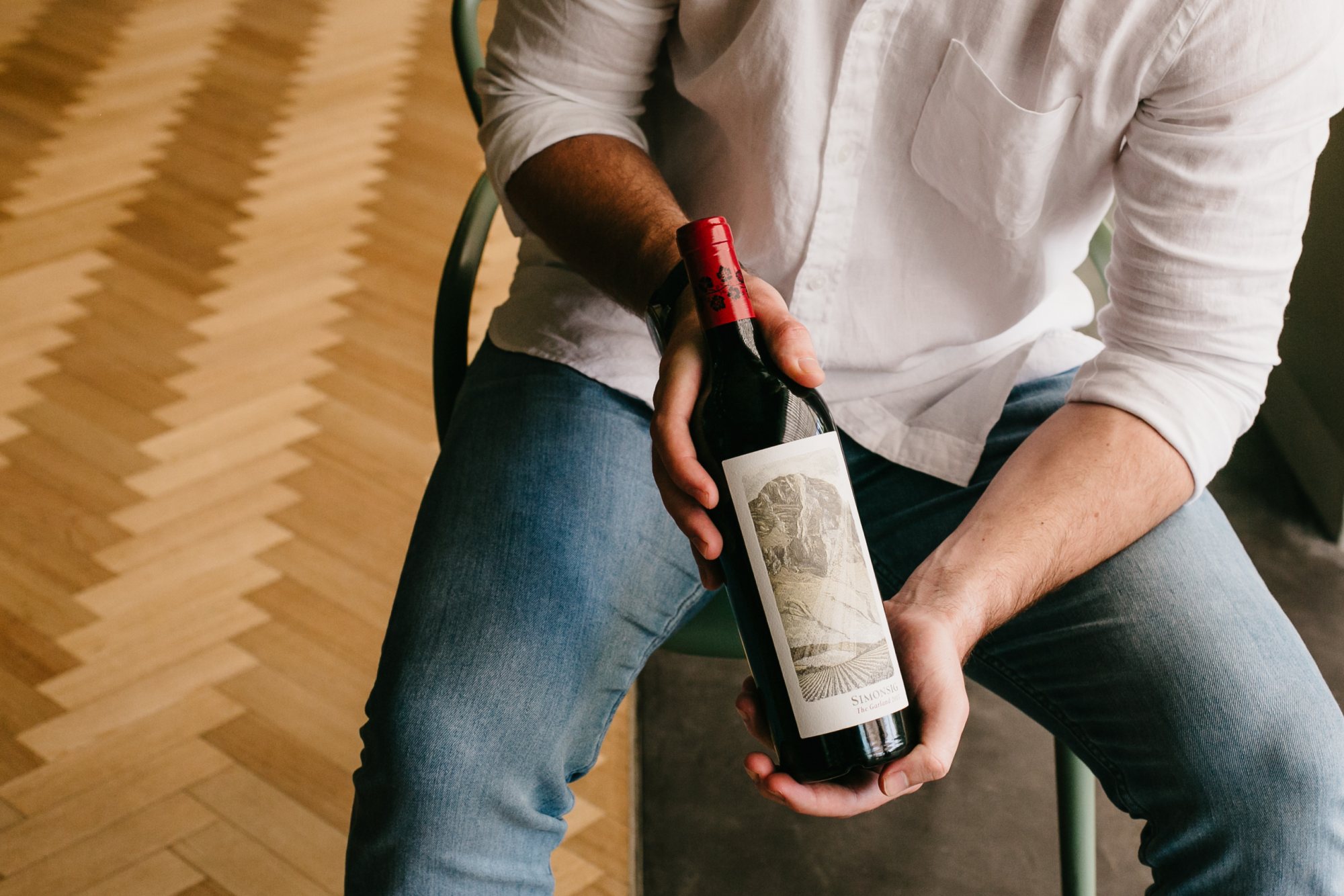 Person holding a wine bottle from Simonsig Family Vineyards
