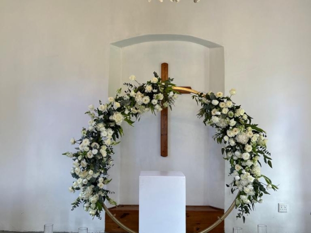 Floral arch design for wedding ceremony with white flowers.