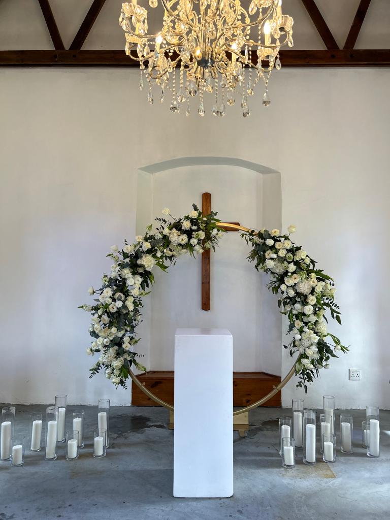 Floral arch with white flowers and candles in a ceremony setup