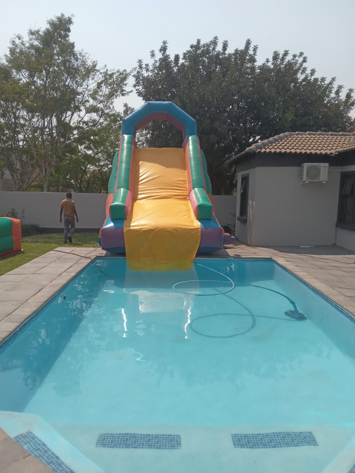 Mini Giant Water Slide by Smart Inflatables beside a swimming pool
