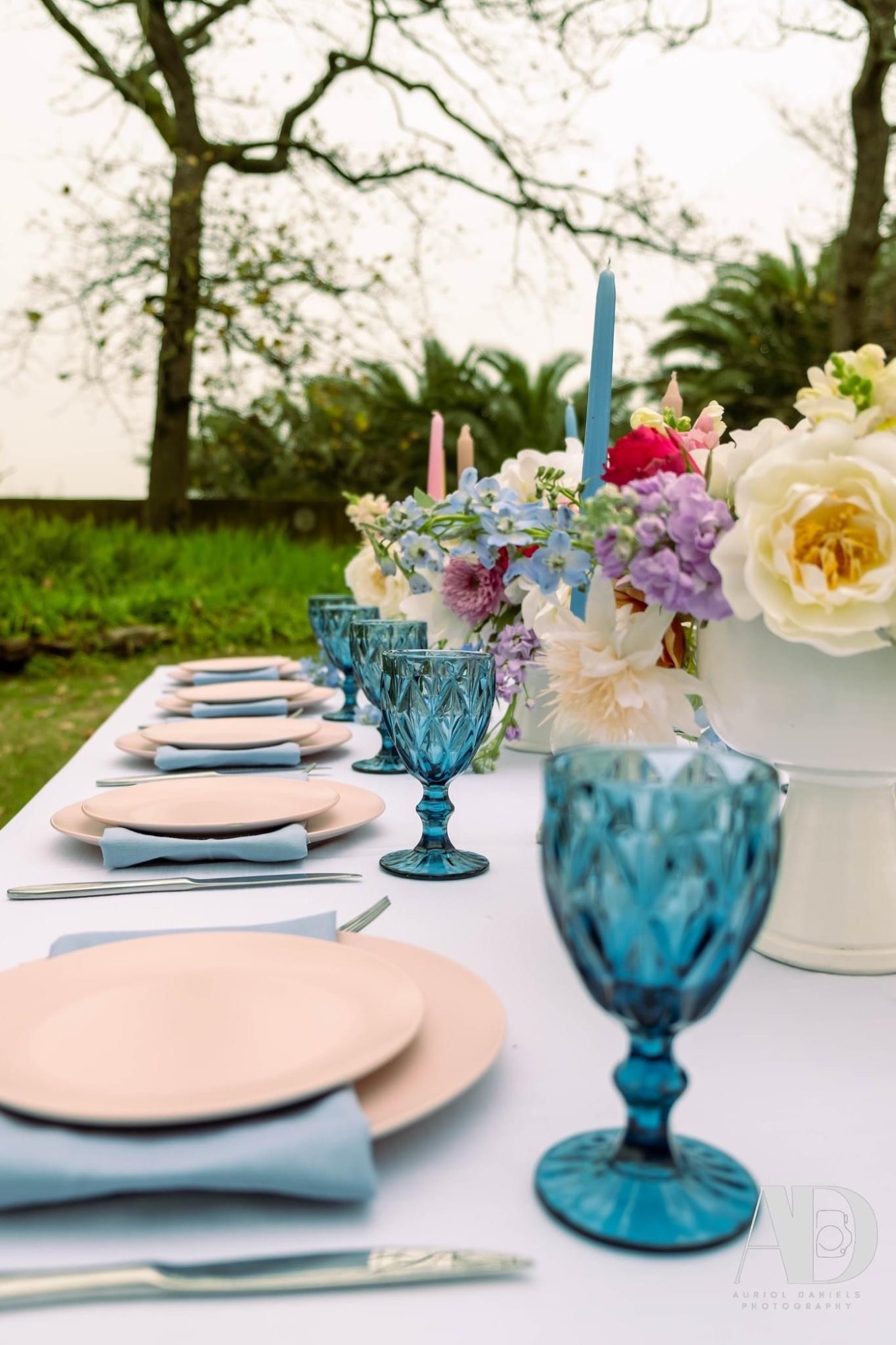 Table set with pink plates and blue glassware with flowers