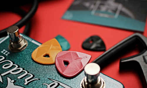 Various colourful guitar picks on a red background