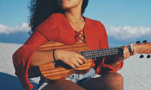 Woman playing a ukulele on the beach