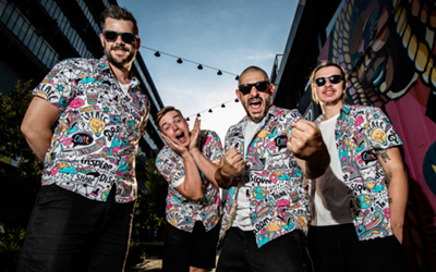 Four musicians in colorful shirts posing outdoors