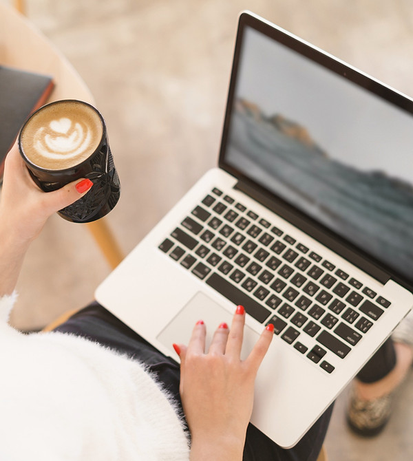 Person holding a coffee while using a laptop