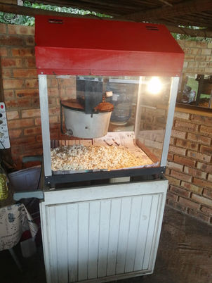 Popcorn machine with kernels and a red top in a rustic setting.