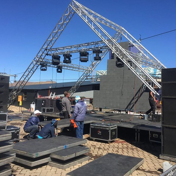 Crew assembling a stage and lighting rig outdoors