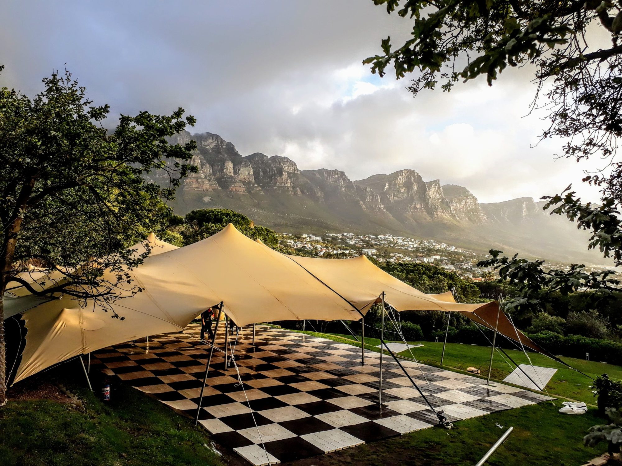 Stretch tent setup on a grassy area with mountains in the background