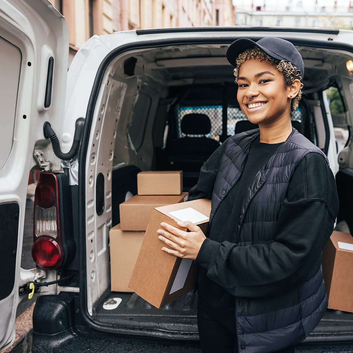 A delivery person holding a package by a delivery van