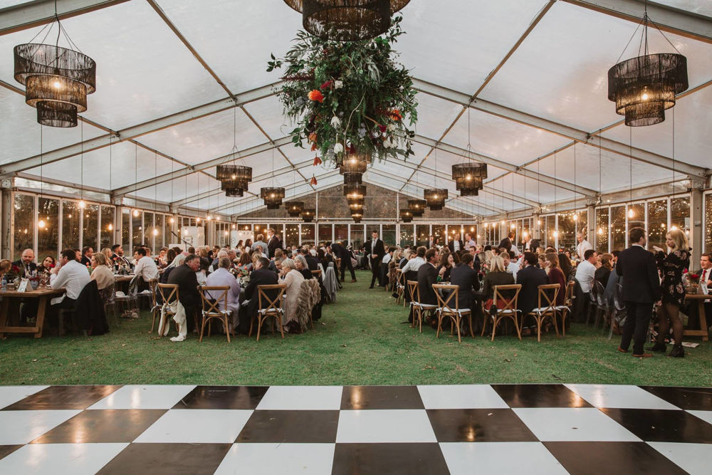 Large marquee event setup with tables and floral decor