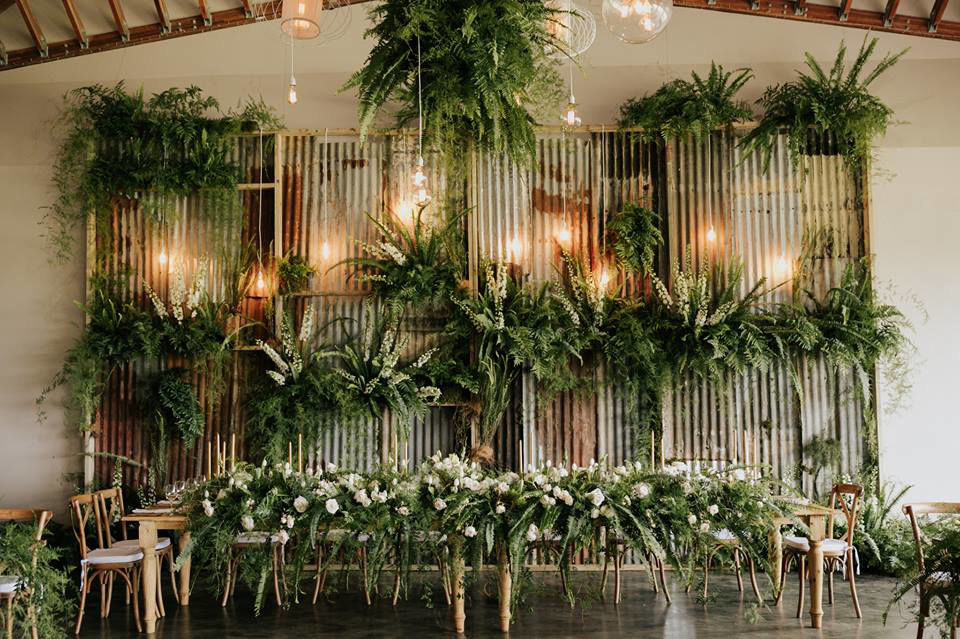Floral backdrop with greenery and white flowers at an event.