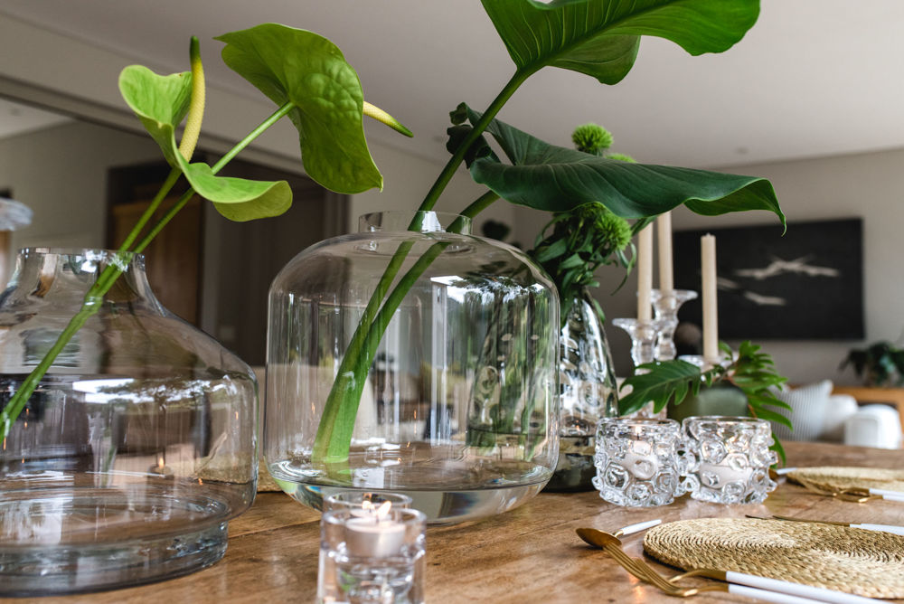 Glass vases with greenery on a wooden table