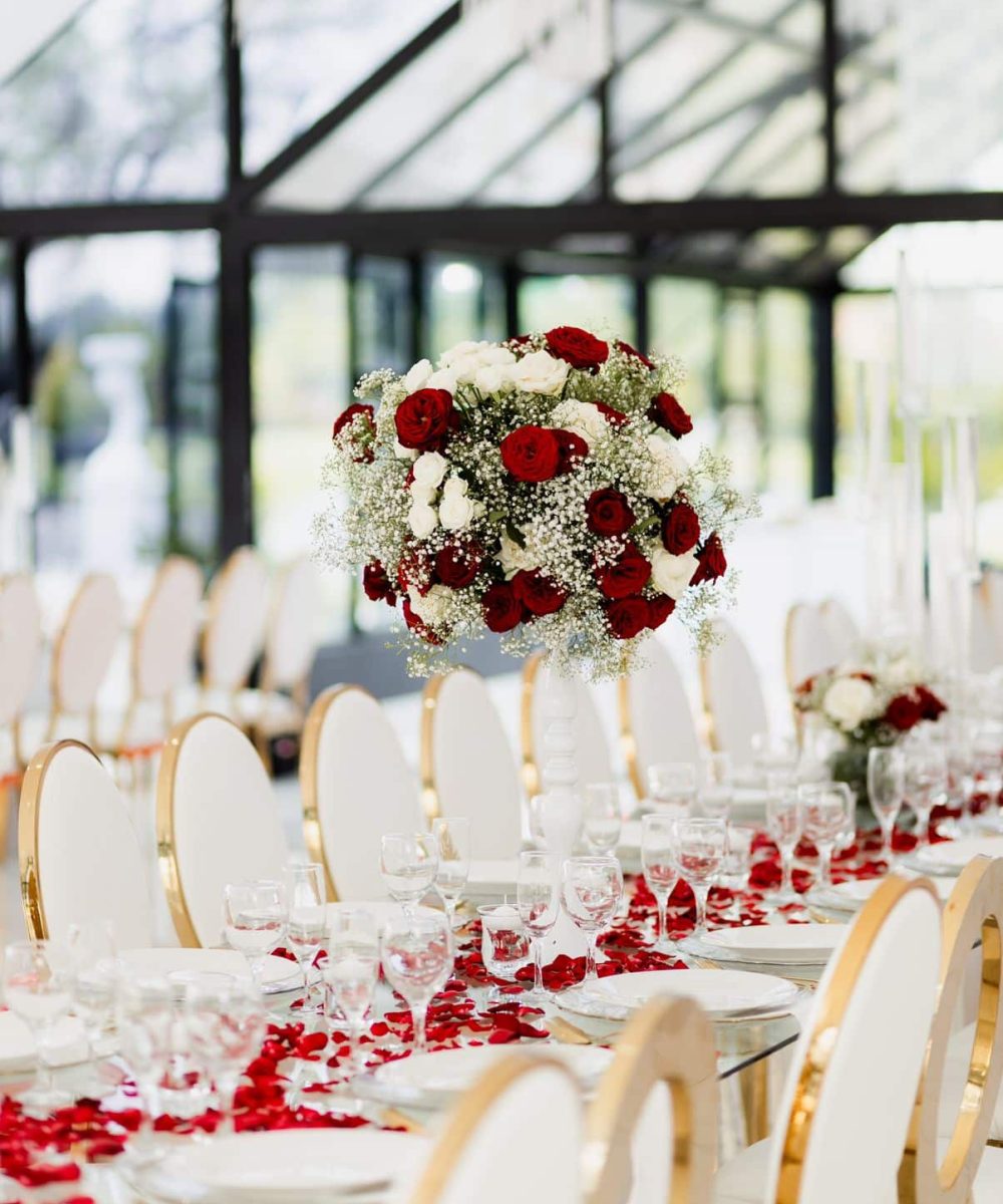 Floral centerpiece with red roses and white flowers above a dining table.