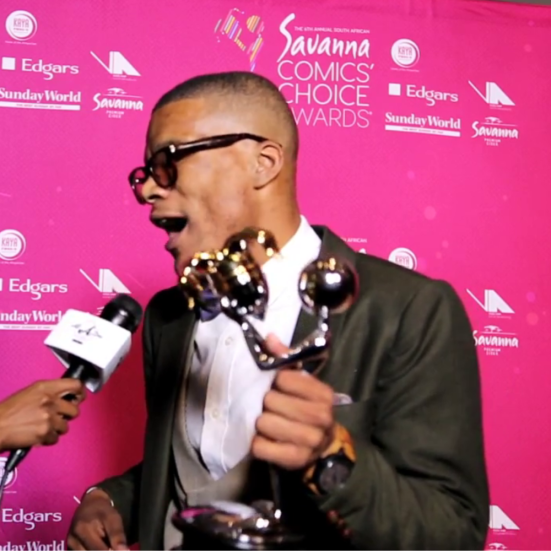 Comedian in a suit holding an award at an event