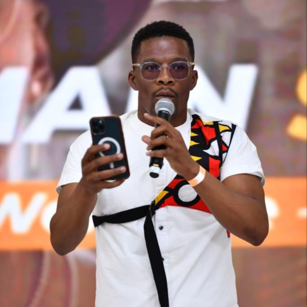 Comedian on stage with a microphone and phone