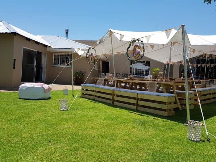 Outdoor party setup with a tent and wooden tables.