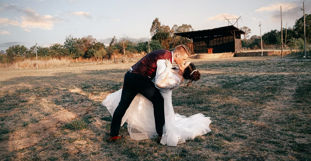 Couple sharing a kiss in a wedding setting, outdoor scene.