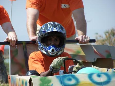 Child racing in a soapbox cart with helmet