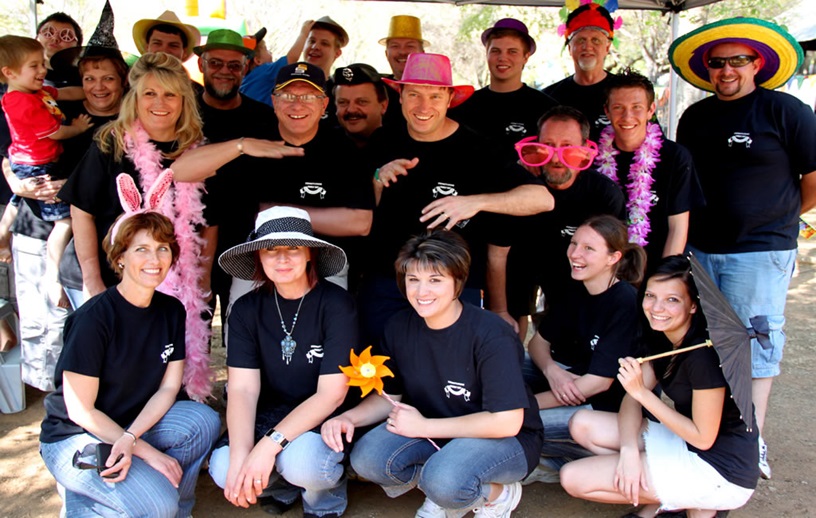 Group of people in matching shirts with playful props at a team-building event
