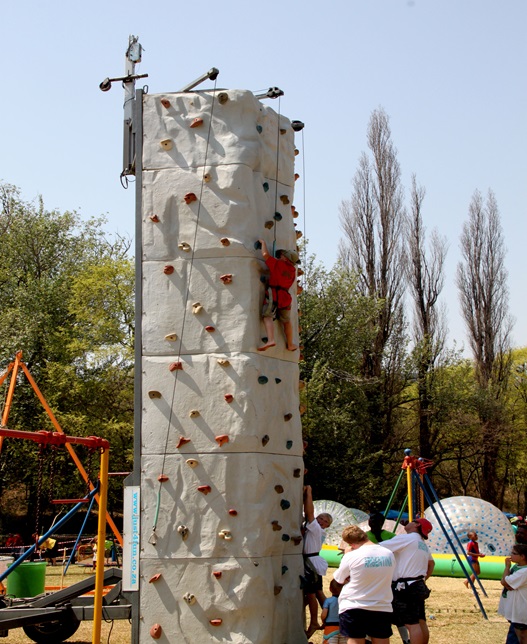 Participant climbing a rock wall with team support