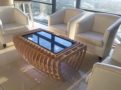 A modern lounge setup with a wooden coffee table and white chairs.