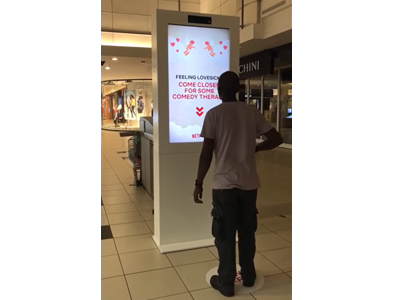 A person interacting with a digital kiosk displaying promotional content.