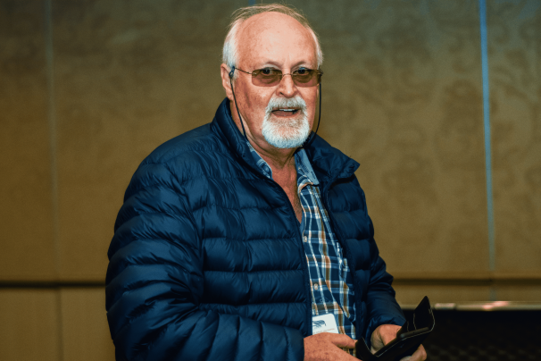 A man with glasses wearing a blue jacket at an event.